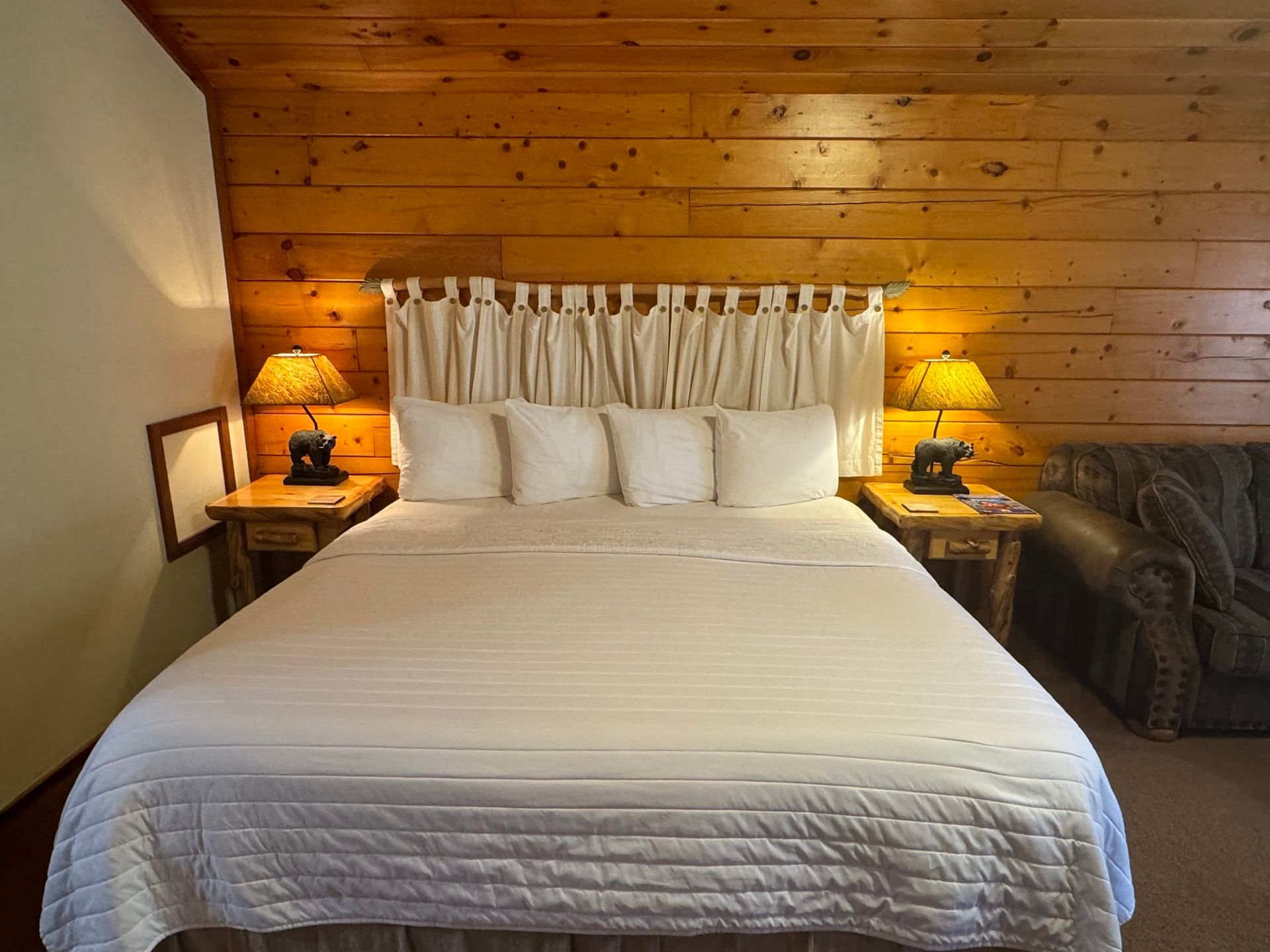 A bedroom with a king size bed and wood paneled walls
