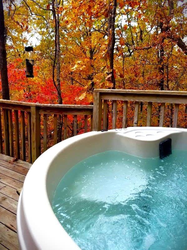 A hot tub on a deck with trees in the background