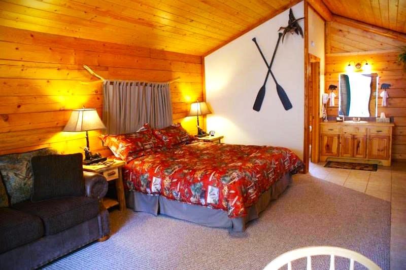 A bedroom in a log cabin with a bed and a couch