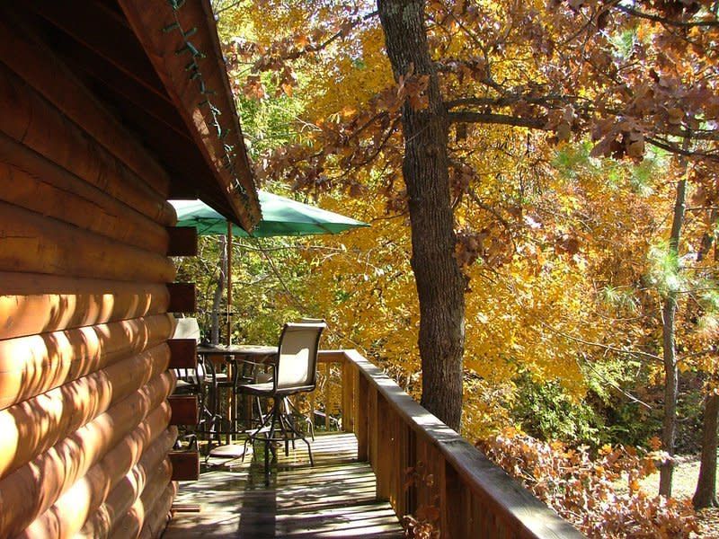 A wooden deck with a table and chairs and a green umbrella