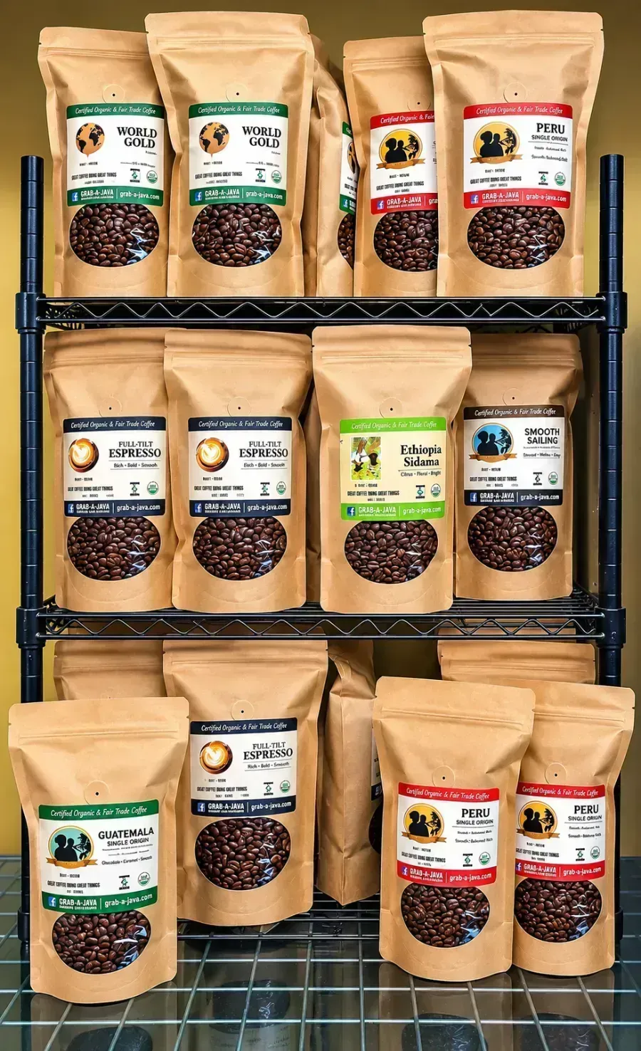 Assorted coffee bags on a black metal shelf, showing different labels and roast colors.