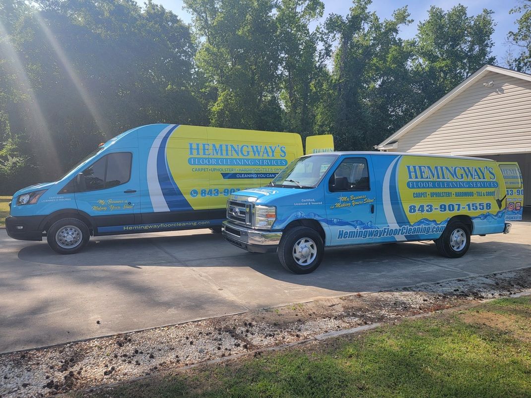 Two company vans, blue and yellow, parked outside a house. 