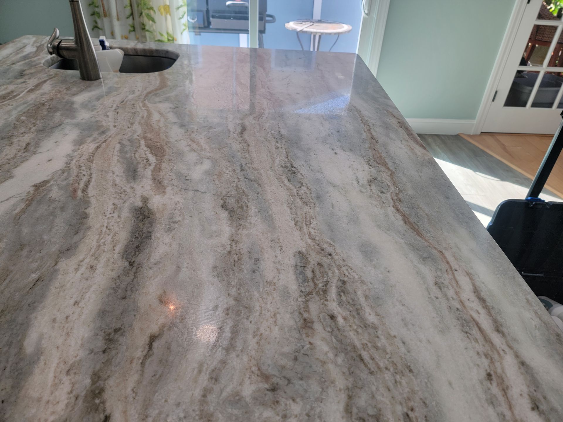 Granite countertop with swirling beige and brown patterns, sink and faucet visible.