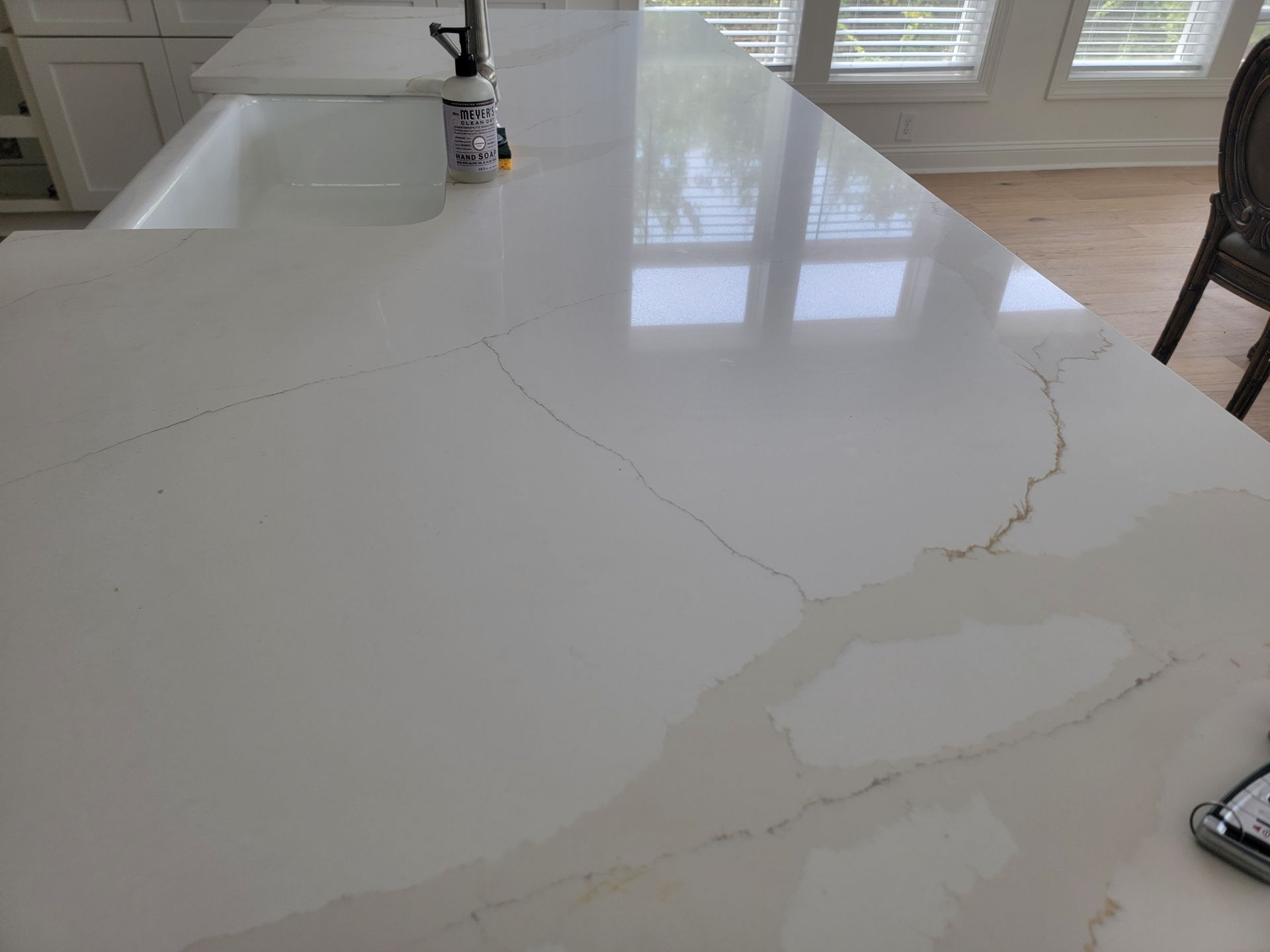 White kitchen countertop with beige veining and a built-in sink.