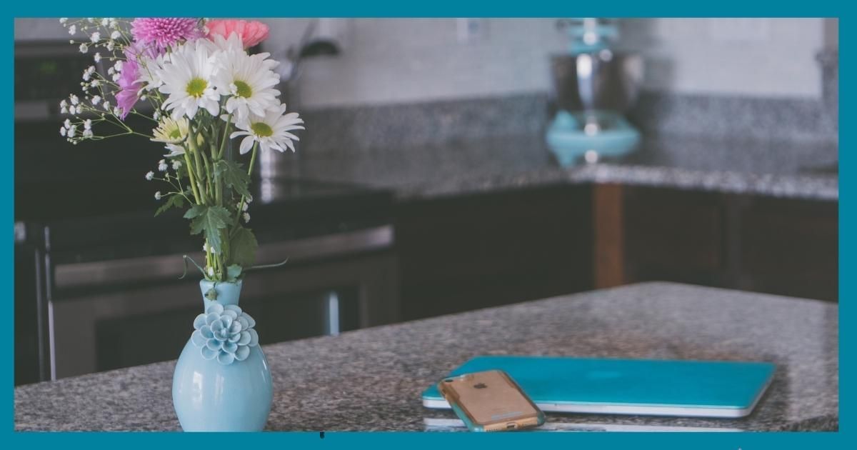 Blue vase of white and pink flowers on a table beside a notebook and phone in a modern room