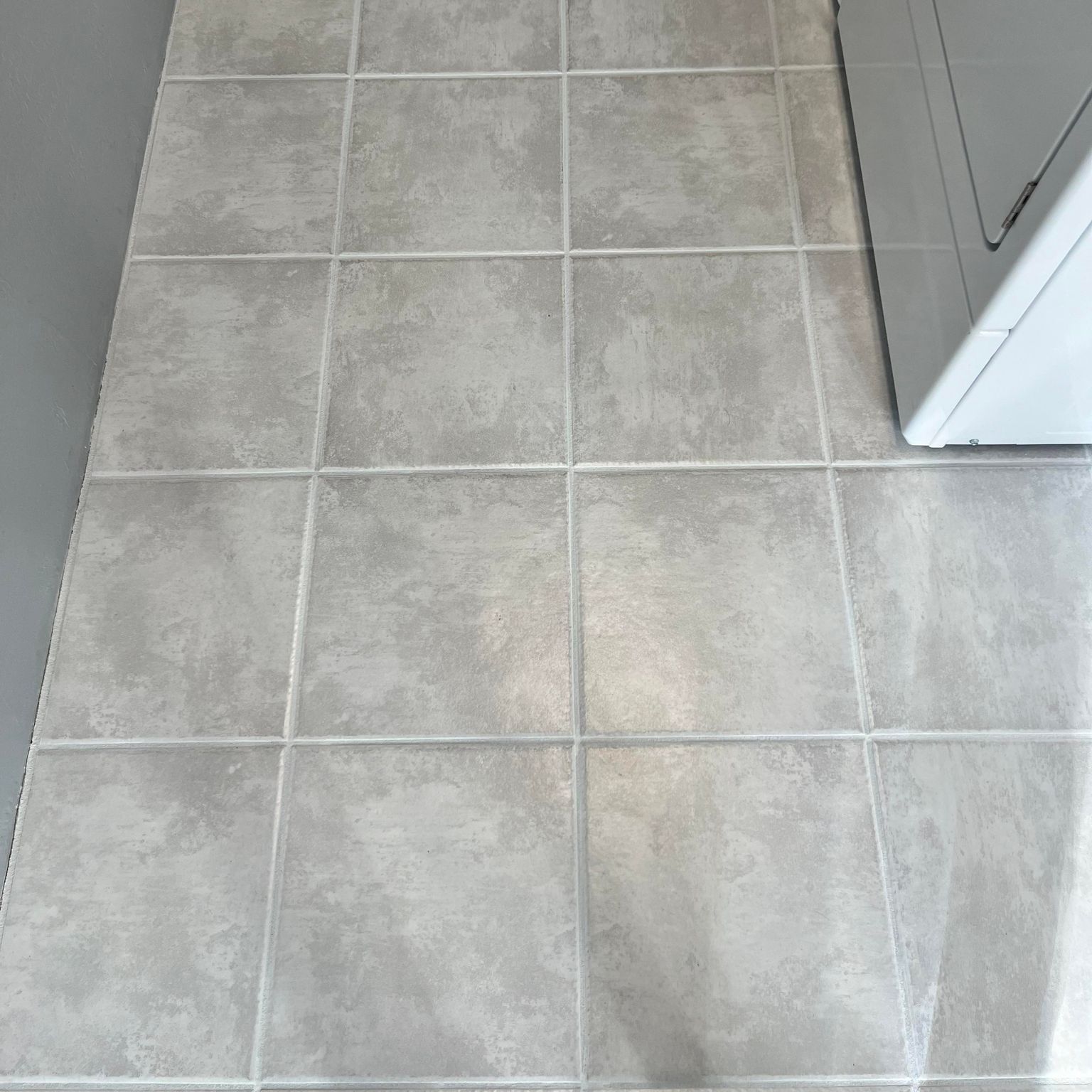 Gray square tile floor with a washing machine.