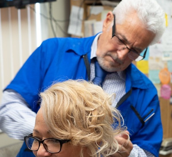 Mr. Carmine cutting woman's hair
