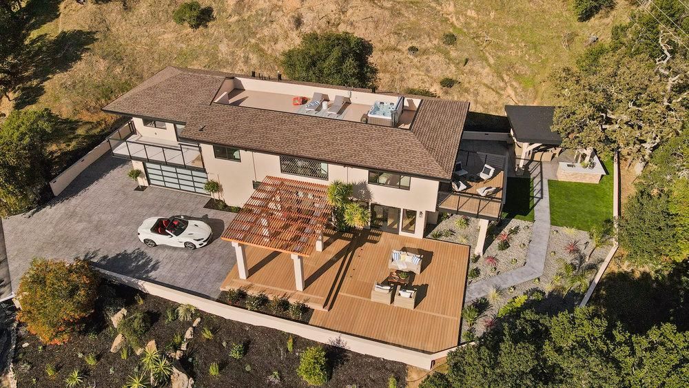 An aerial view of a large house with a car parked in the driveway.