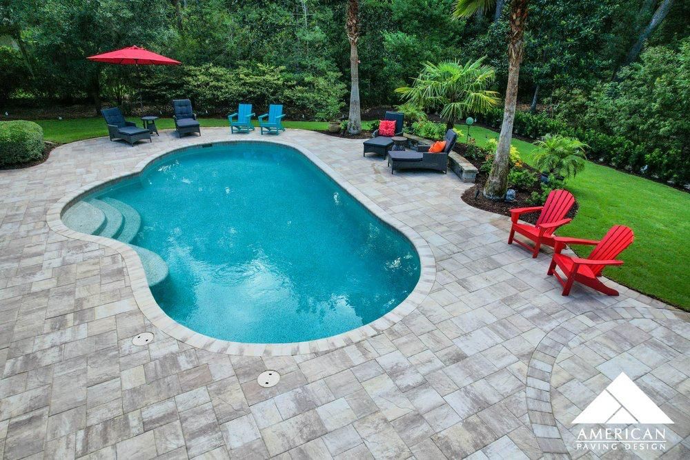 A large swimming pool surrounded by chairs and a red umbrella