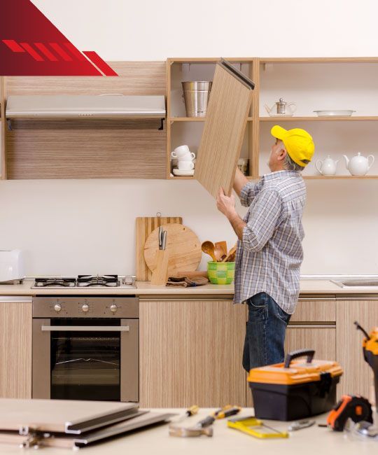 A man is standing in a kitchen holding a piece of wood.