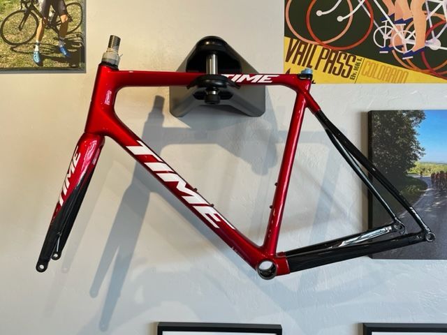 Red and black TIME carbon fiber bicycle frame hanging on a wall.