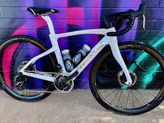 White road bike with black and gold wheels against a colorful graffiti wall.