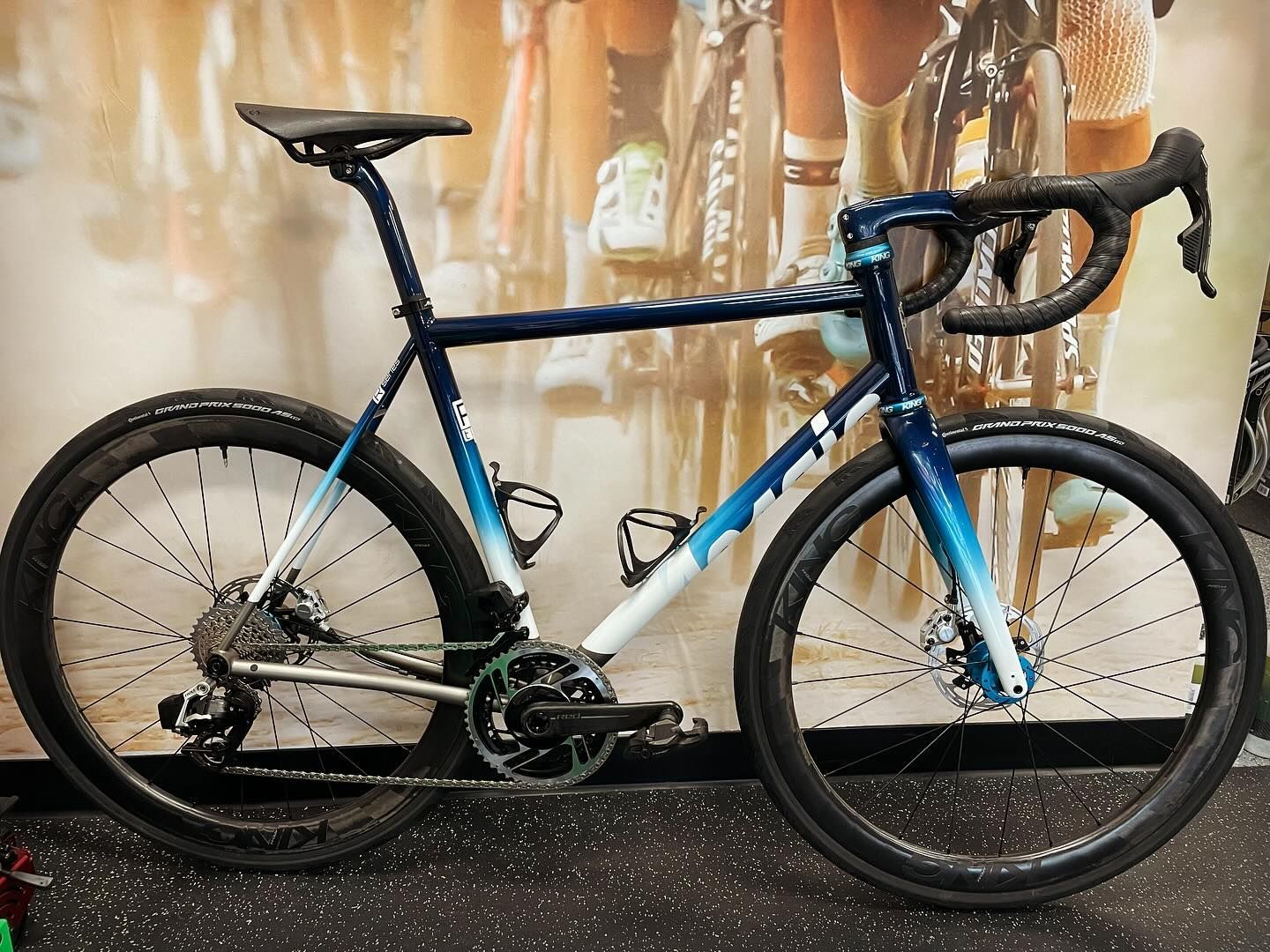 Blue and white gradient road bike with black wheels and tires, parked indoors.
