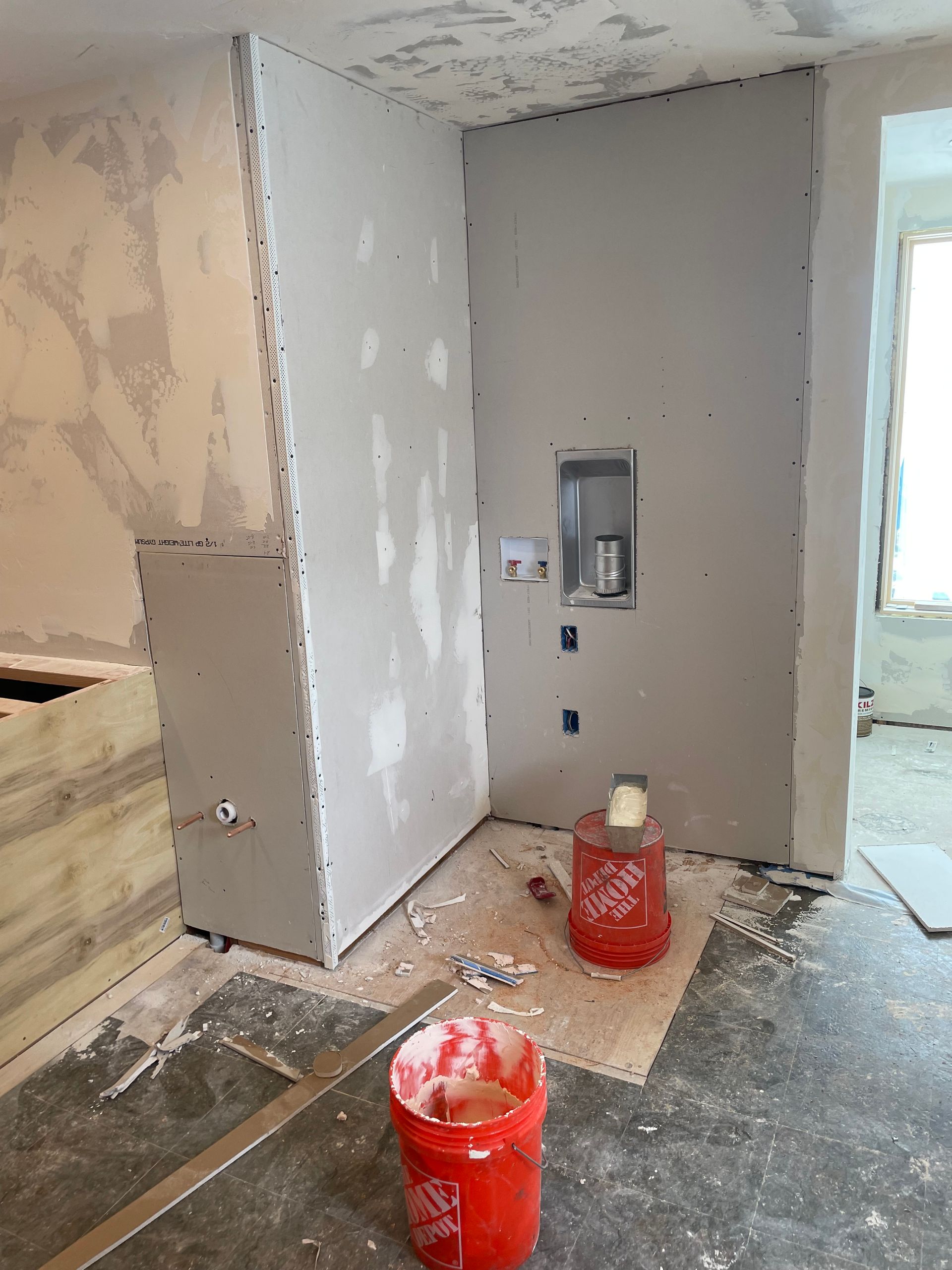 Partially renovated bathroom with drywall, plumbing, and red utility buckets on the floor