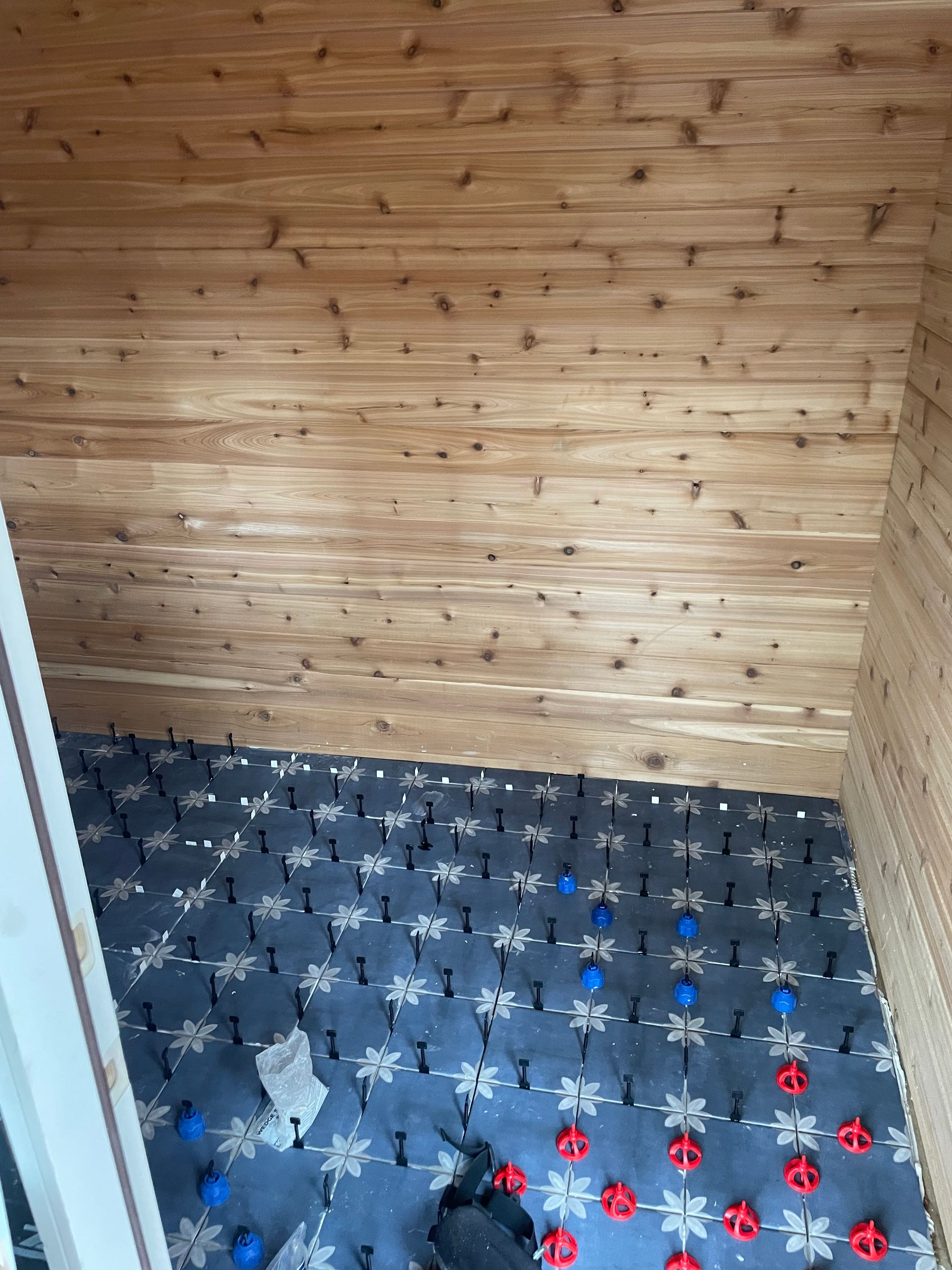 Wood-paneled room corner with gray carpet and scattered blue, red, and white plastic pieces