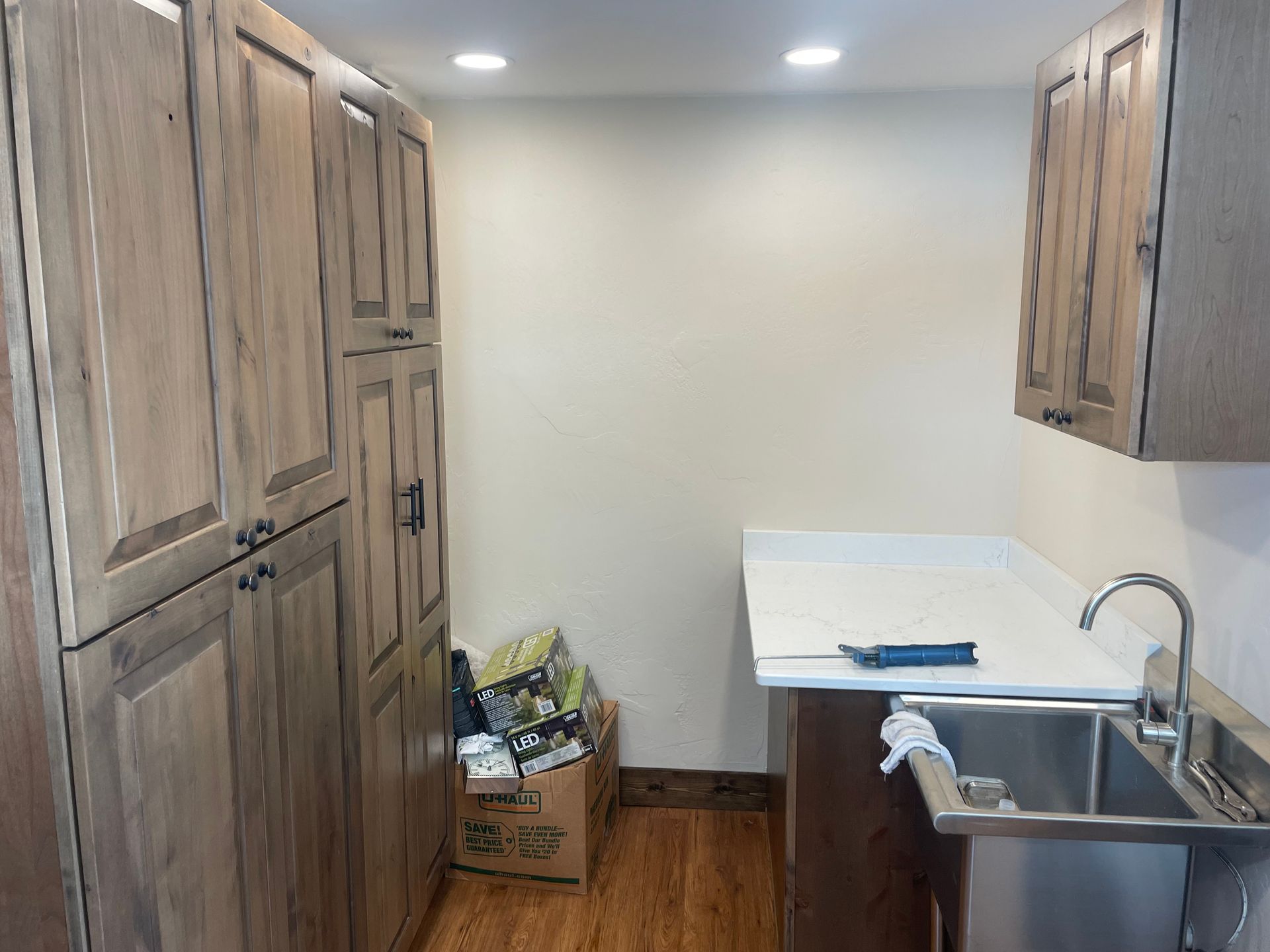Narrow kitchen with wood cabinets, sink, and countertop in a small room.