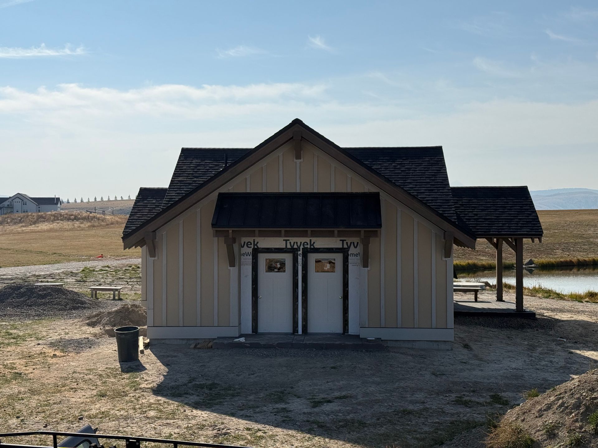 Small rustic building with dark roof and white doors in a barren open landscape under a blue sky