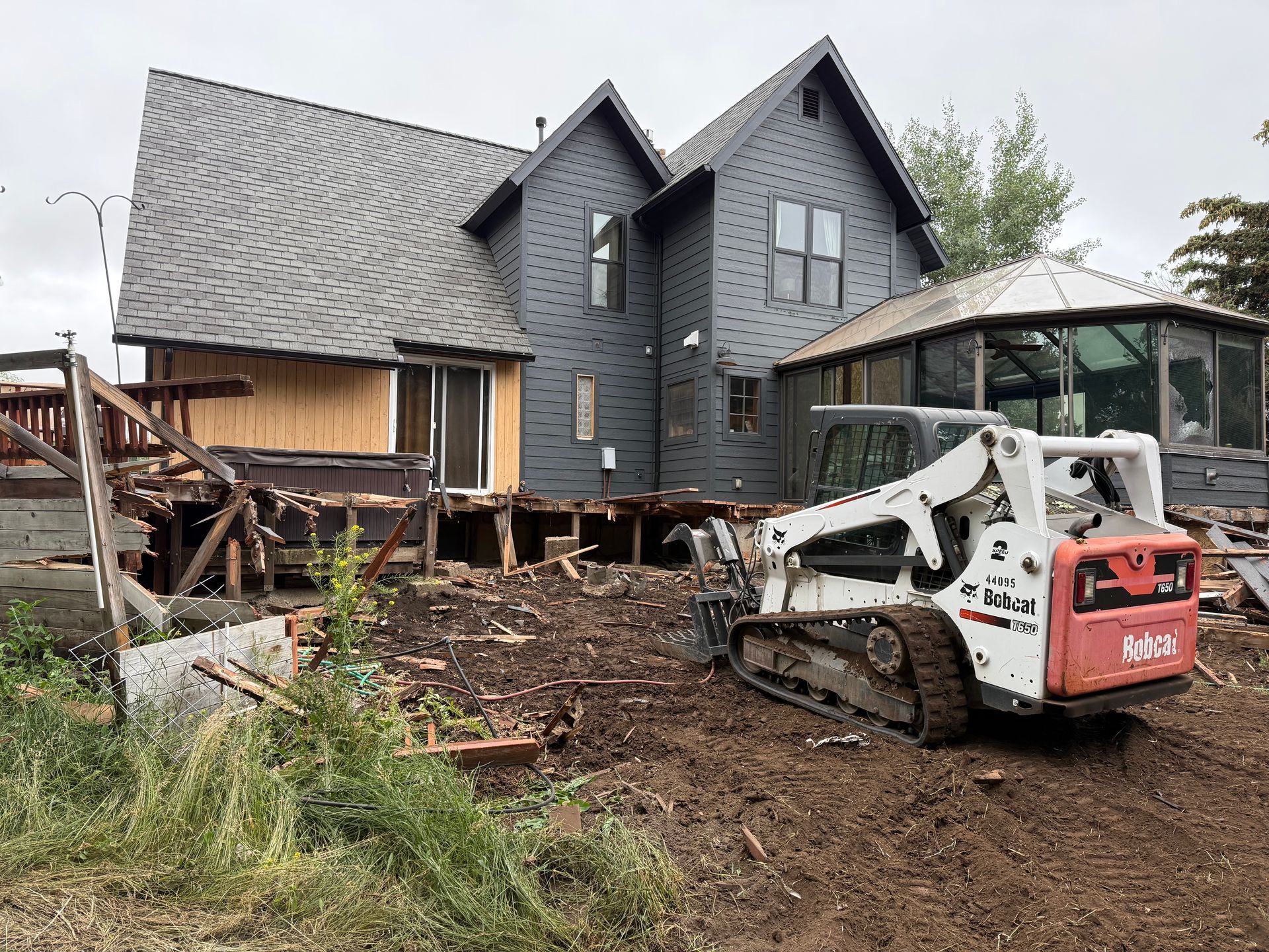 House under construction with a skid-steer loader clearing mud and debris in front of it