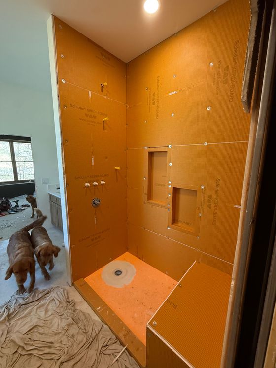 Orange tiled bathroom shower with built-in shelves and a dog standing in the doorway