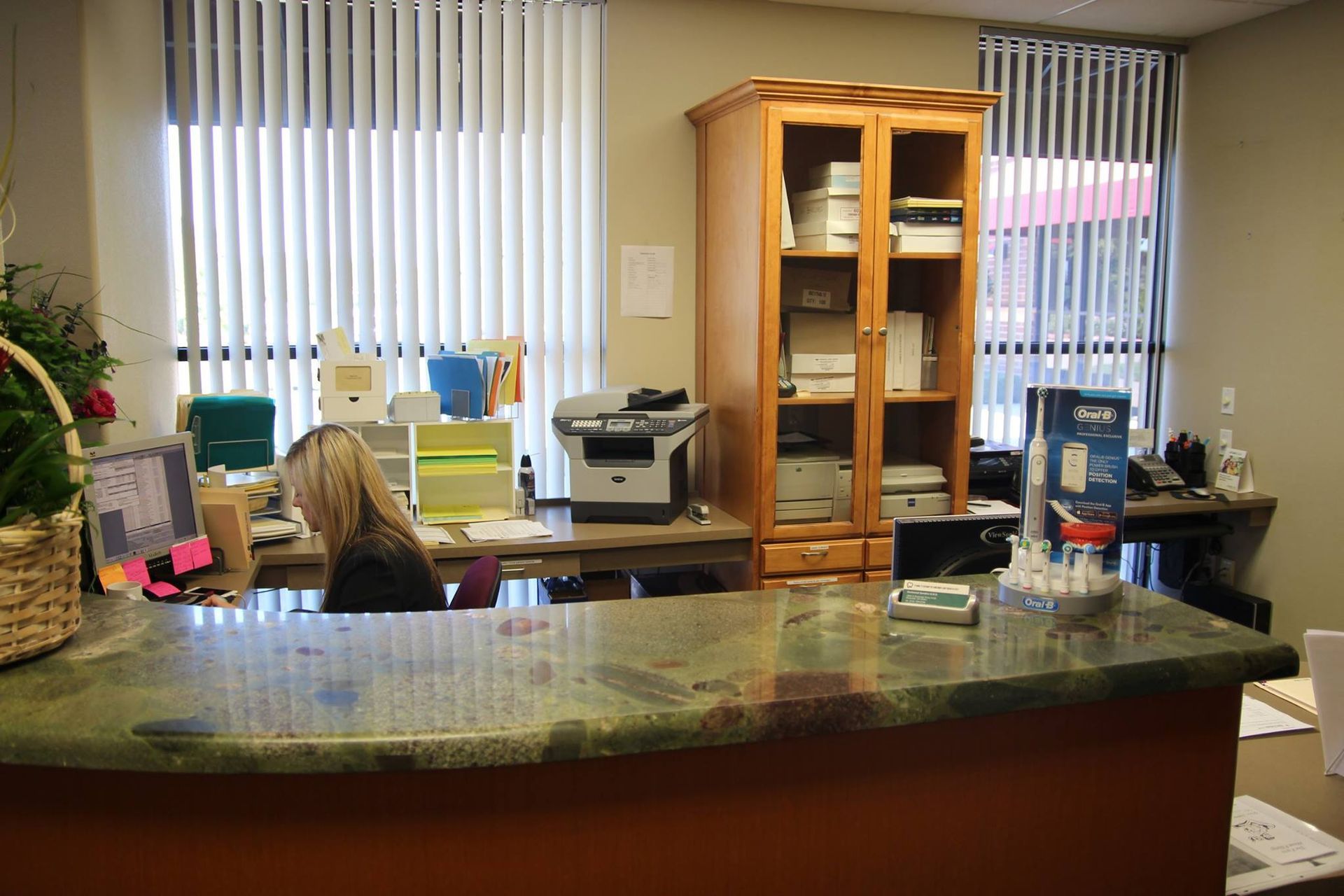 A woman is sitting at a desk in front of a counter in an office.
