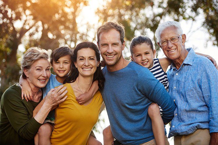 A large family is posing for a picture together in a park.