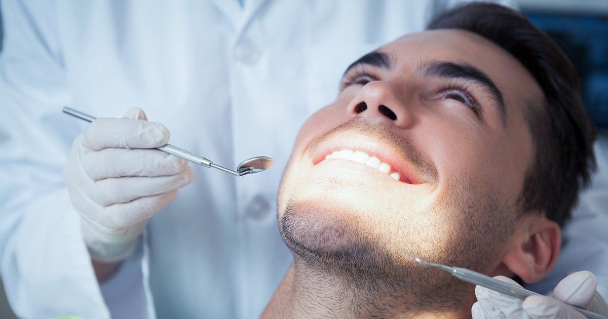 A man is getting his teeth examined by a dentist.