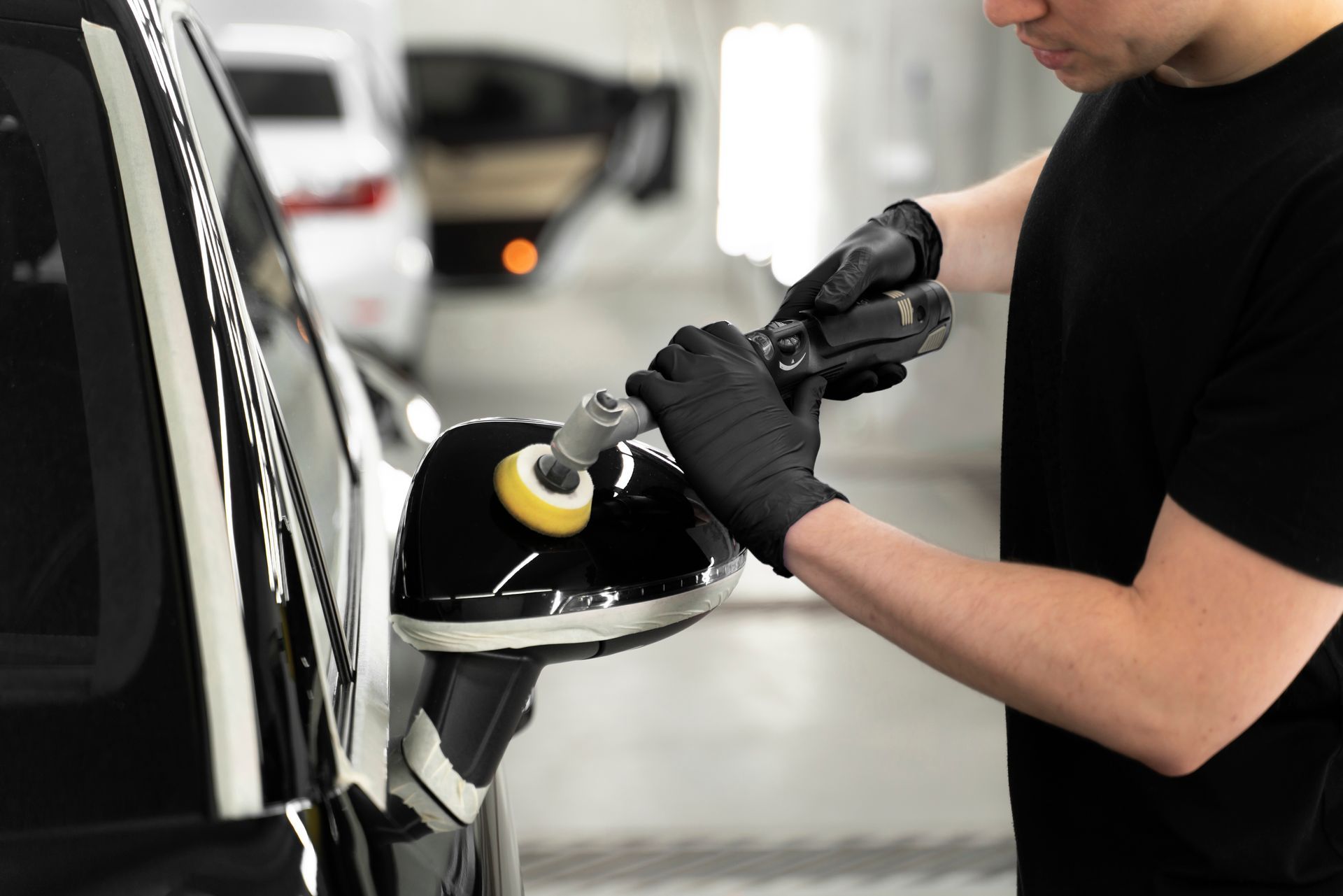 Person applying car wax with a blue applicator to a gray car door.