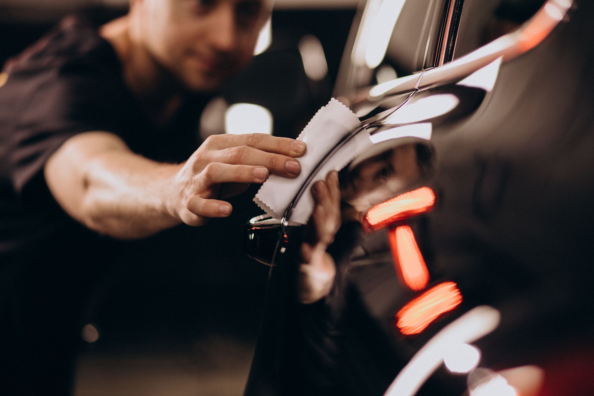 Person cleaning shiny chrome car detail with a white cloth.