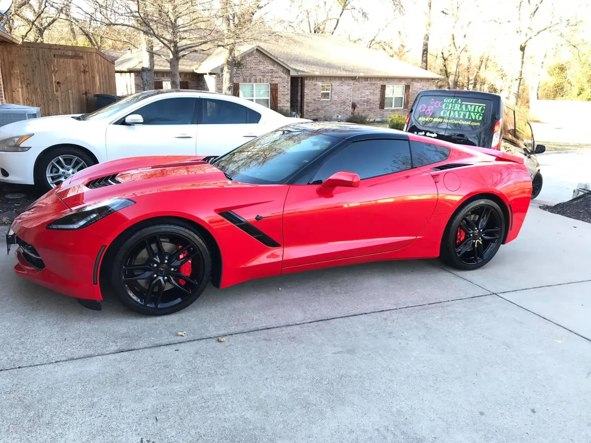 Red sports car parked in a driveway beside a white car, with a house in the background. Red sports car parked in a driveway beside a white car, with a house in the background.