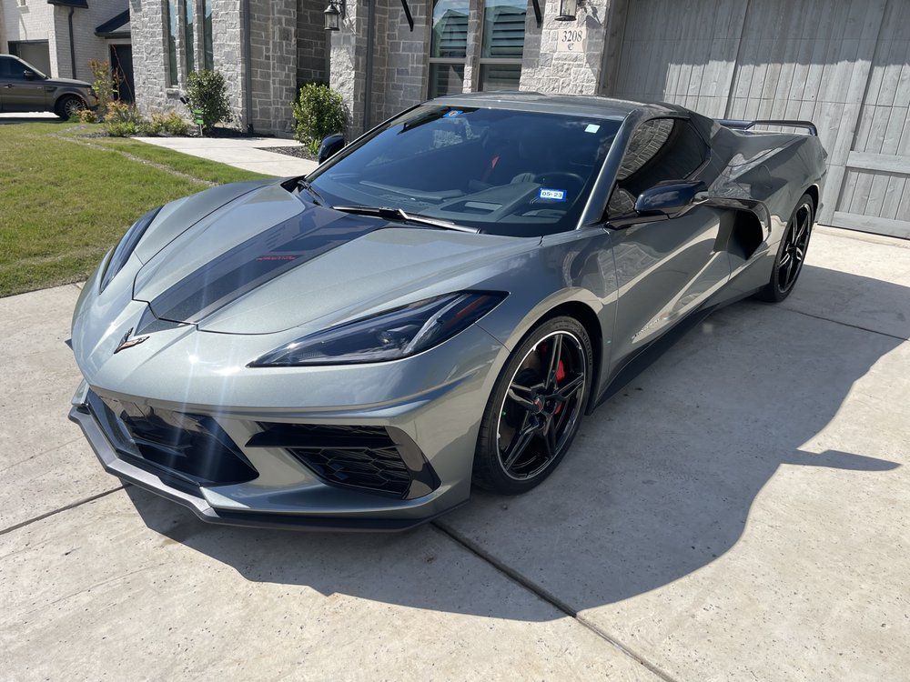 Gray Chevrolet Corvette with black racing stripes parked on a driveway.