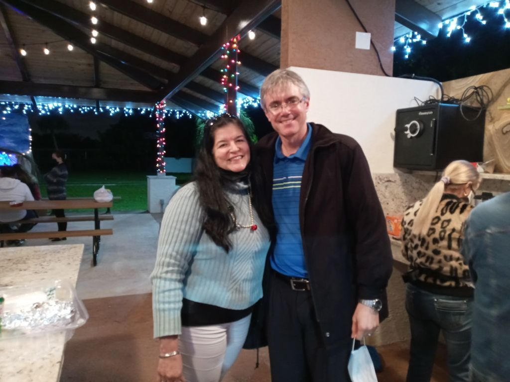 Smiling couple standing together under string lights at an outdoor gathering