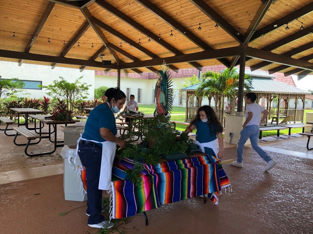 People browsing a colorful outdoor market table under a wooden pavilion