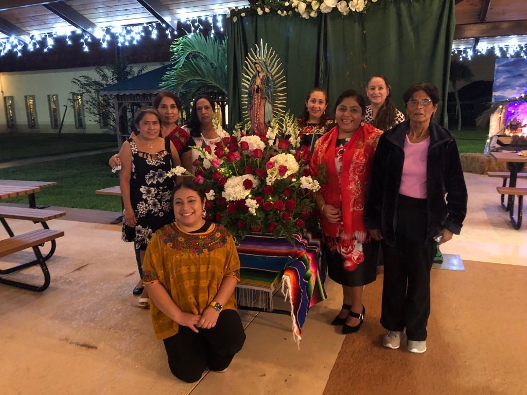 Group posing beside a flower arrangement indoors, with one person kneeling in front.