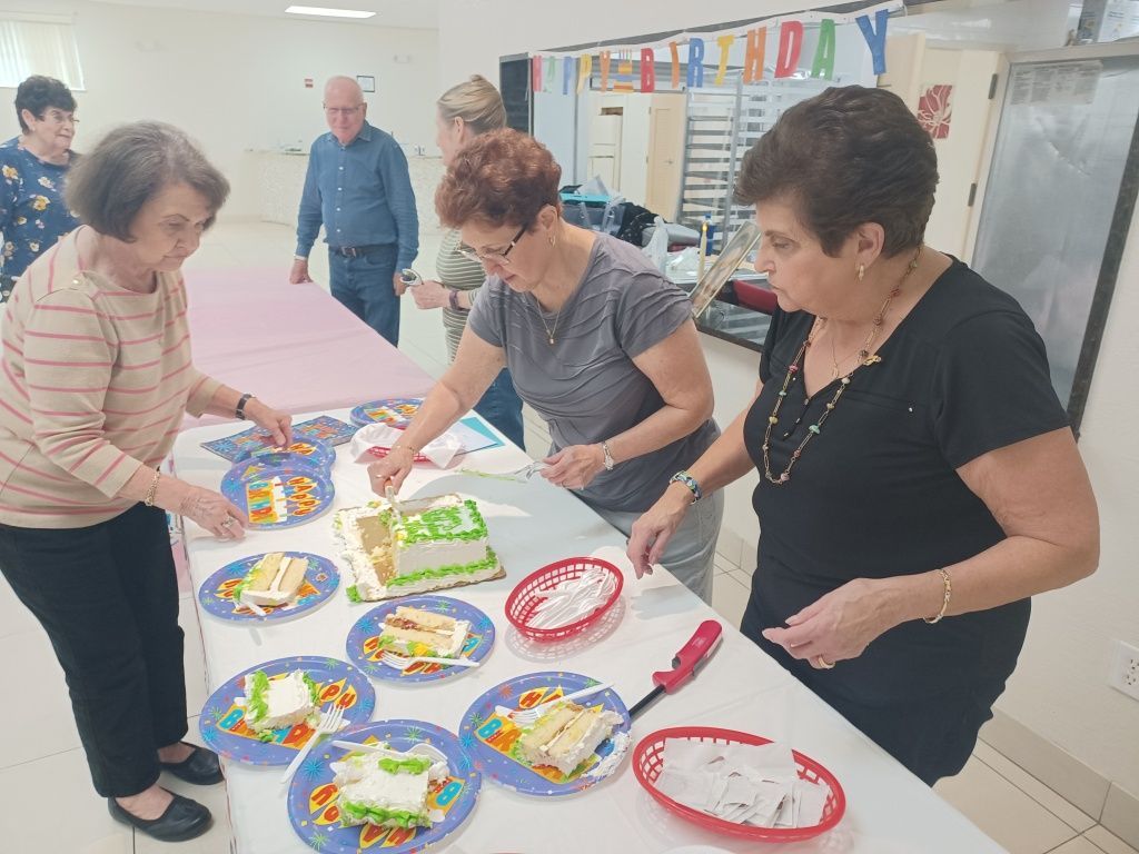 People arranging colorful paper plates on a table in a bright community room
