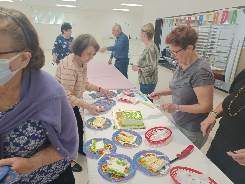 People decorating colorful paper plates at a craft table in a bright community room