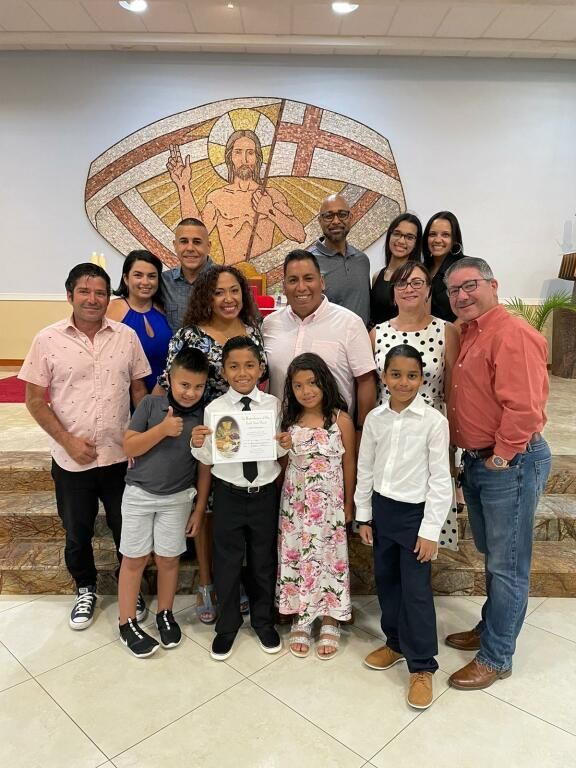 Group portrait of smiling people indoors in front of a colorful mosaic wall