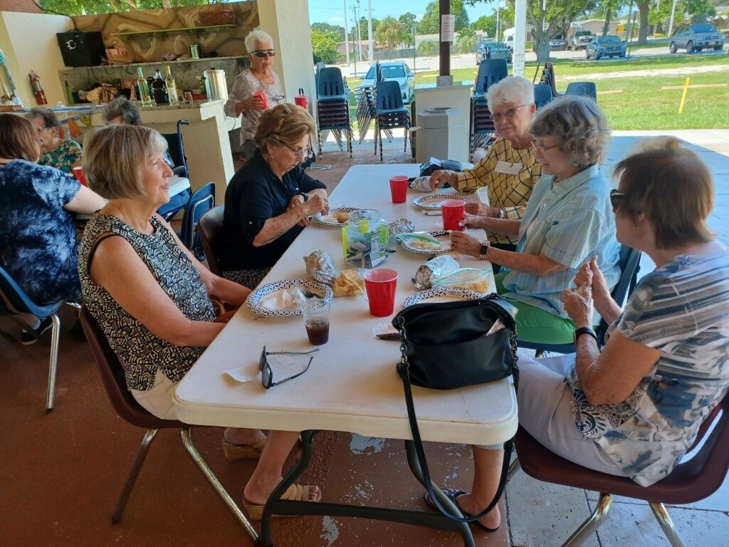 People seated around a picnic table eating and chatting in an open-air café.