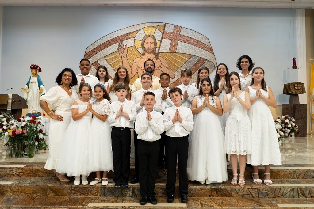Choir group in white outfits posing on church altar before a mosaic backdrop