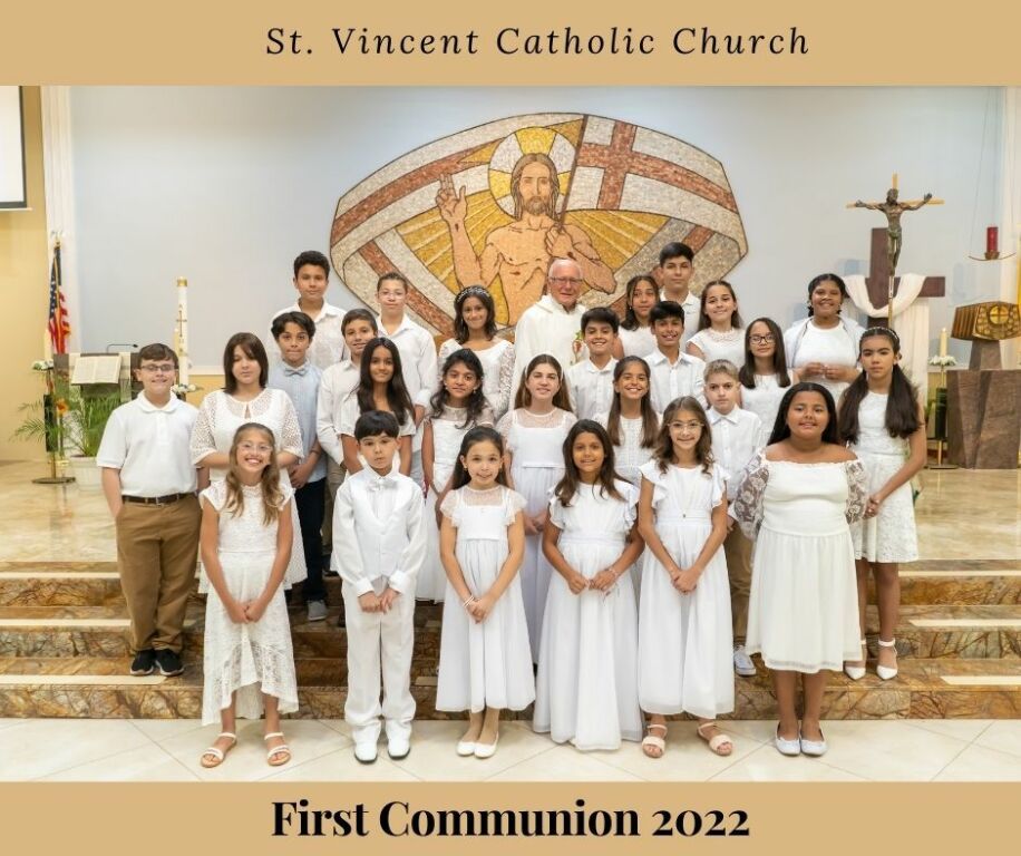 First Communion group photo at St. Vincent Catholic Church before a mural backdrop