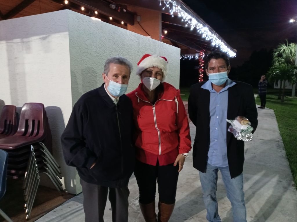 Three masked people posing outdoors at night, one wearing a Santa hat and red jacket.