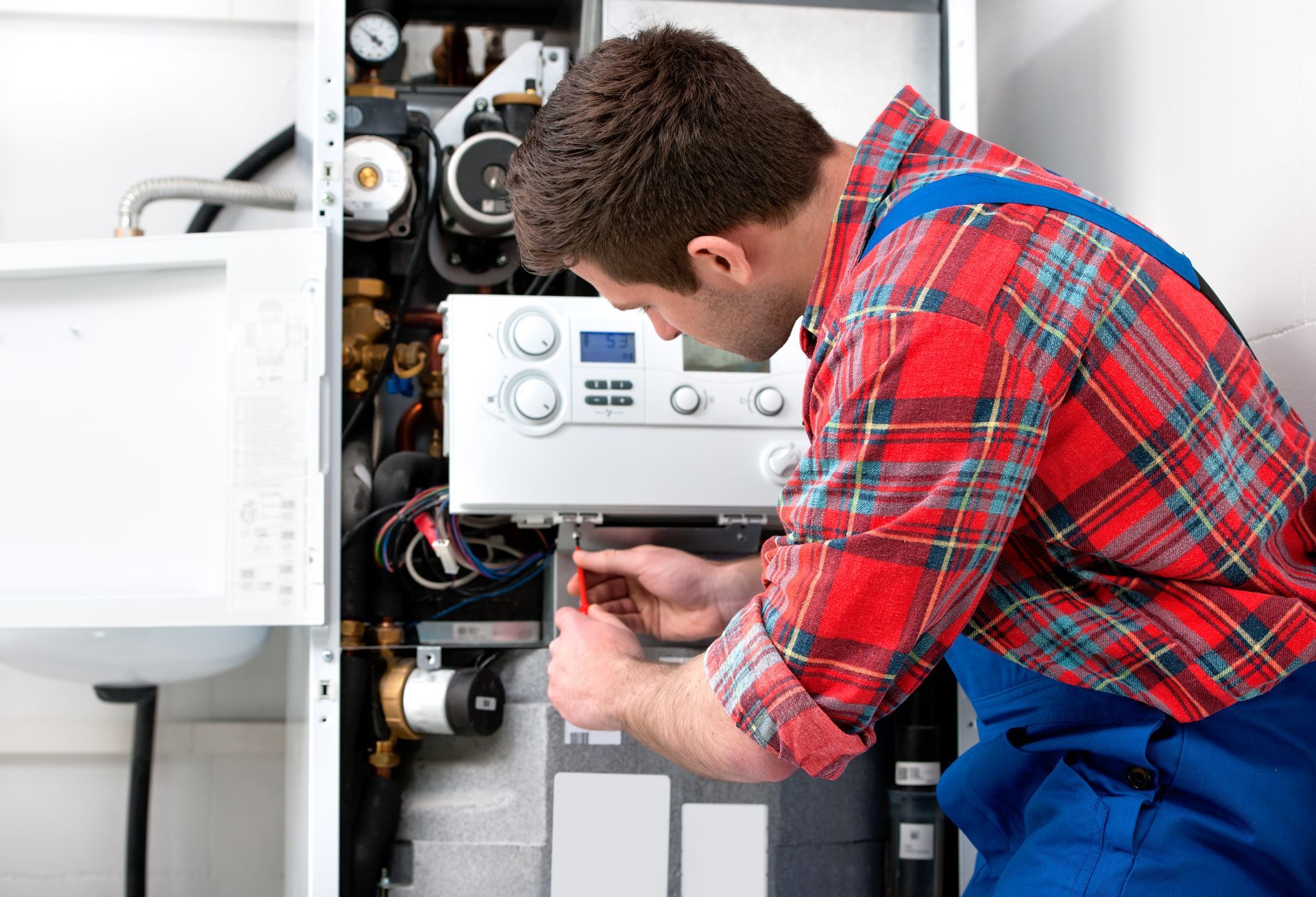 A male technician repairing internal components of a residential heating system.