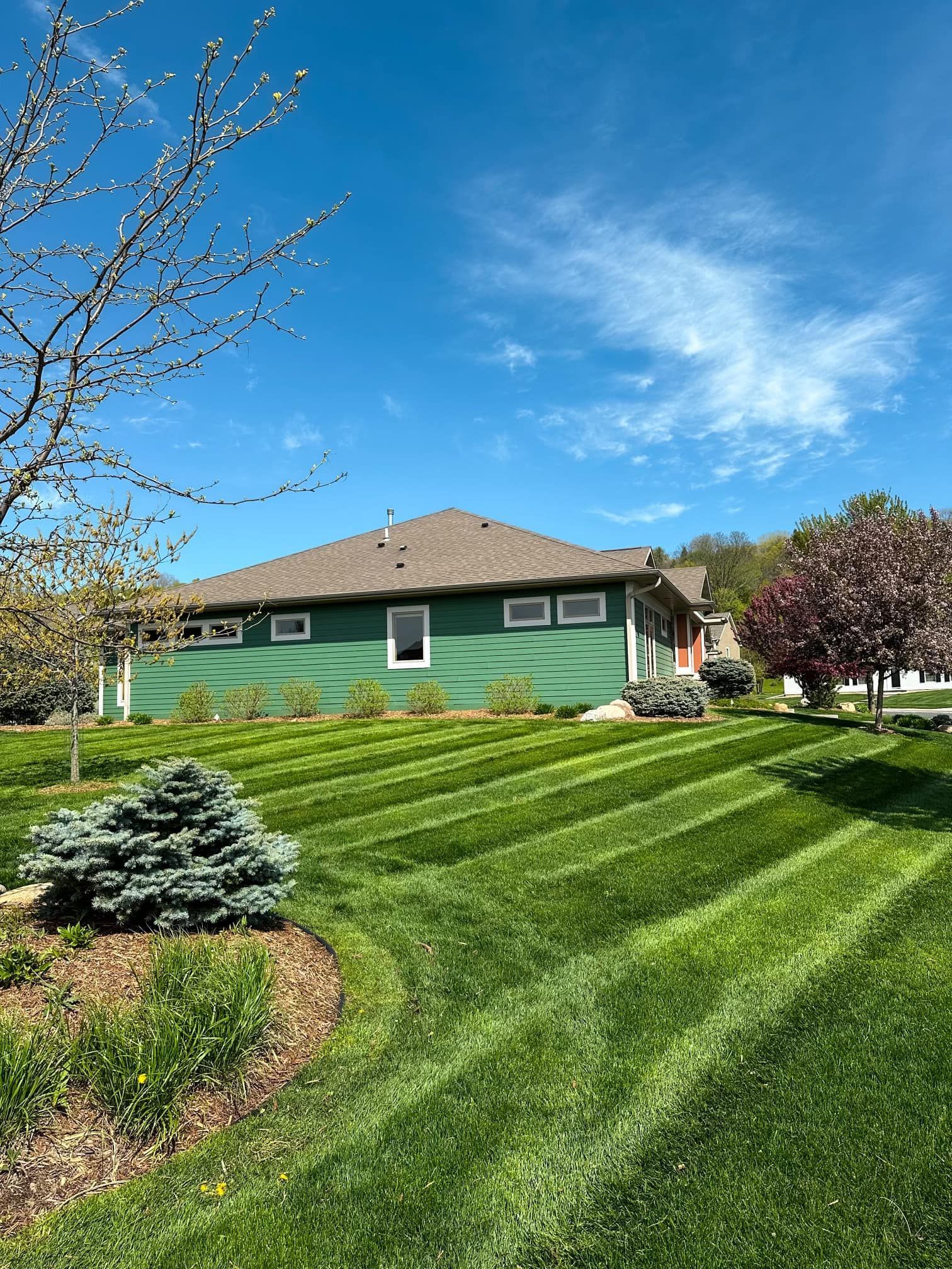 A green house with a lush green lawn in front of it.