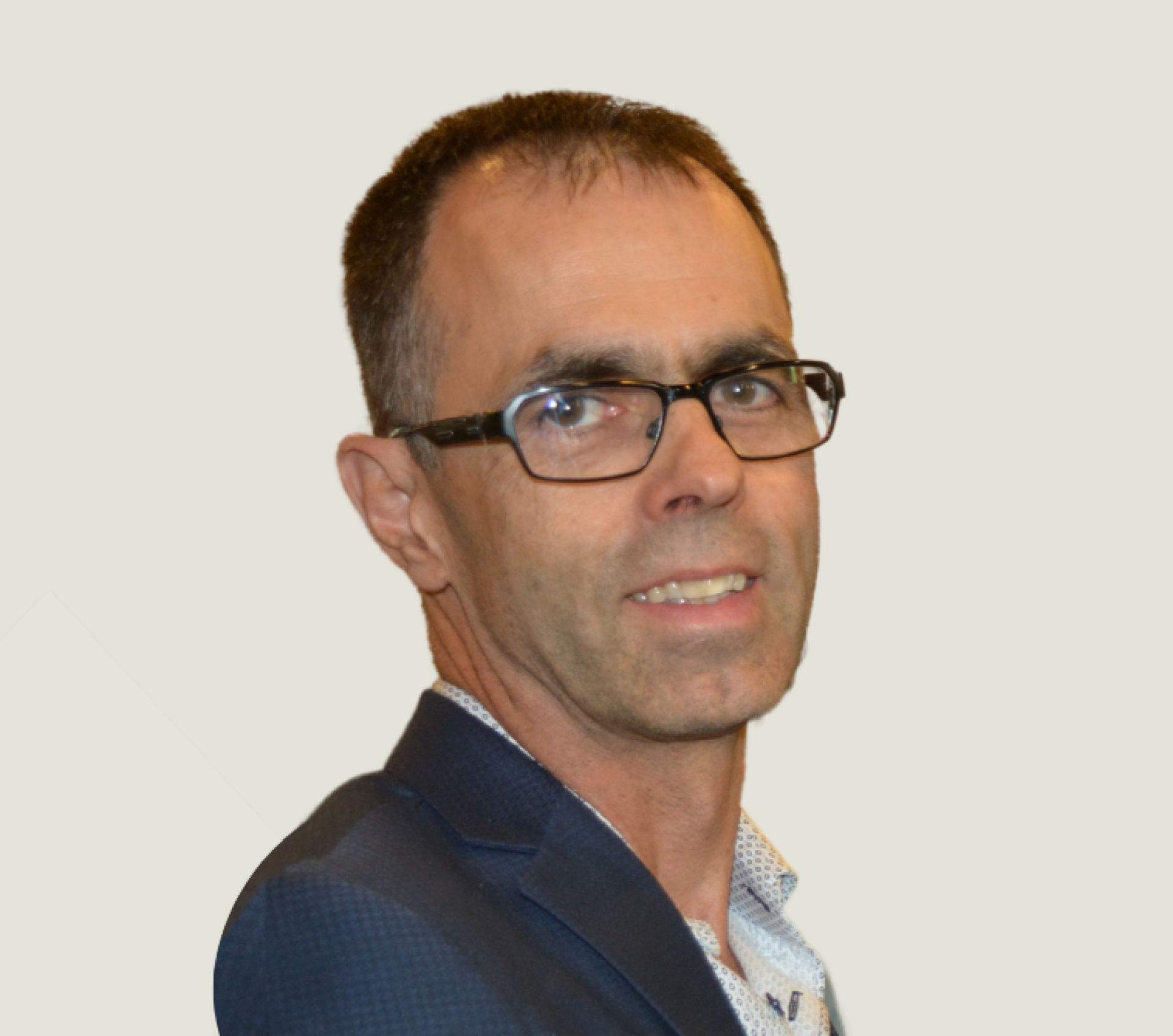 A man wearing glasses and a suit is smiling for the camera