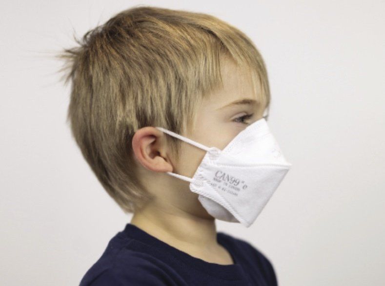 A young boy wearing a face mask that says ffp2 on it