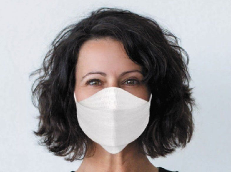 A woman is wearing a white face mask on her face.
