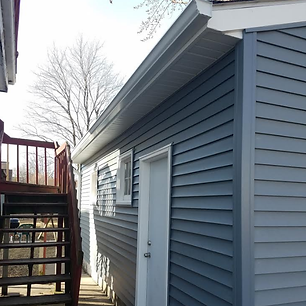 A gray house with a white door and stairs