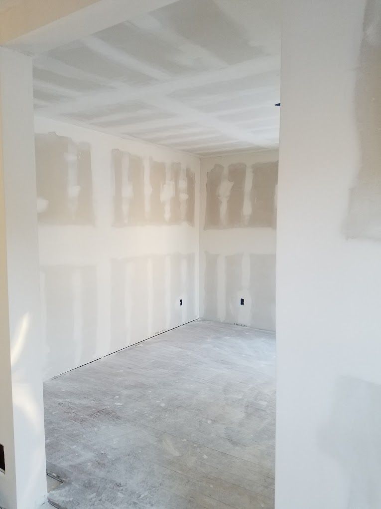 An empty room with drywall on the walls and a concrete floor.