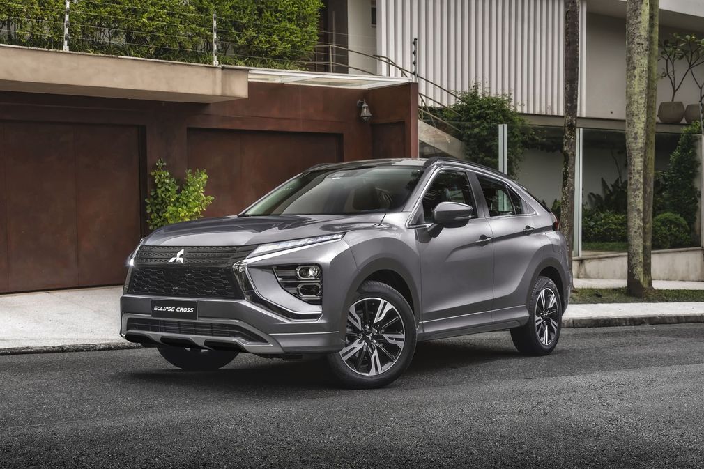 SUV Mitsubishi cinza estacionado em uma rua residencial em frente a garagens modernas.