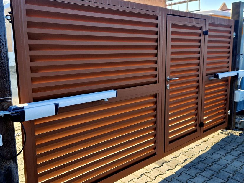 Brown metal sliding gate with horizontal slats and white handles in front of a paved driveway
