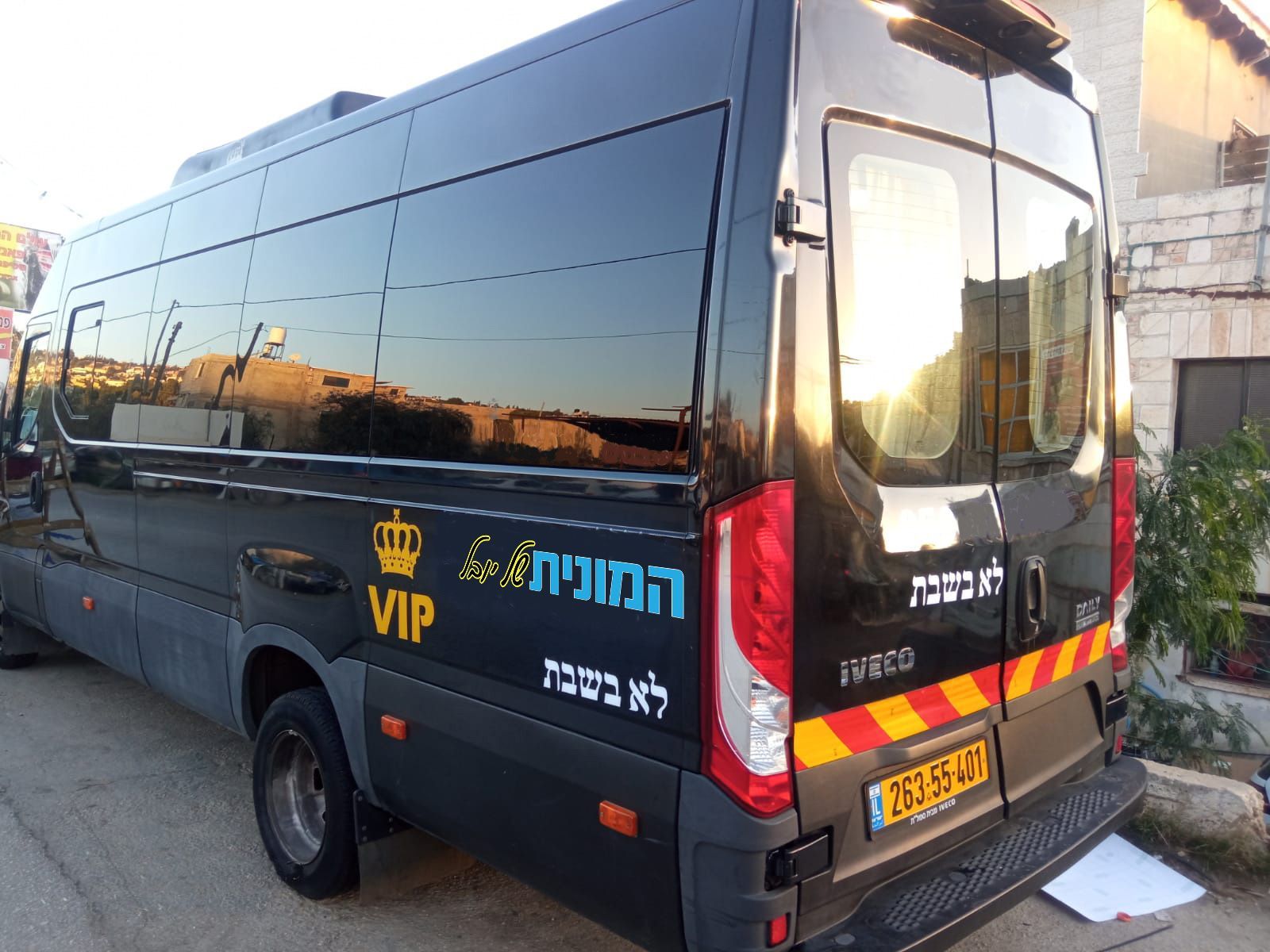 ואן שחור וארוך להסעות עם שטח מטען נרחב עבור הסעות לנתבג. (מתאר ואן שחור, מבט מהצד האחורי)